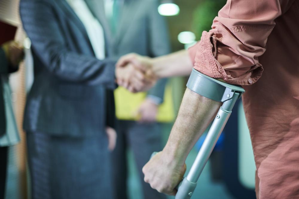 Click to enlarge Man in crutches shakes hands while consulting with a personal injury attorney. 